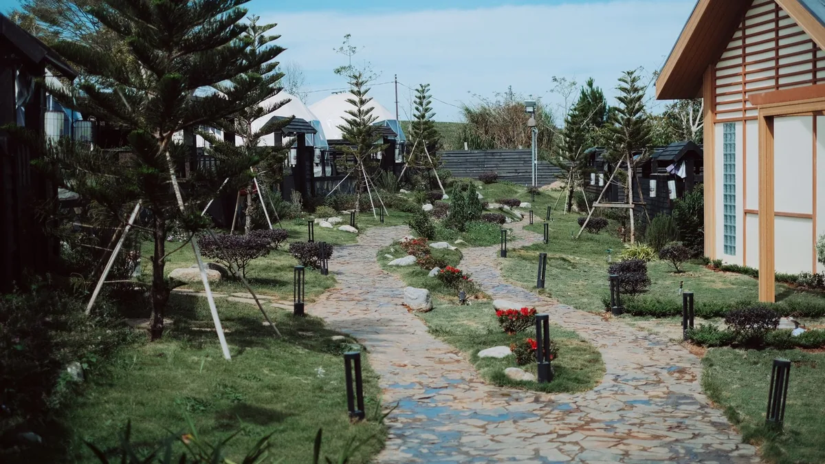 A tranquil Japanese-style garden with stone pathways and a traditional house on a sunny day.